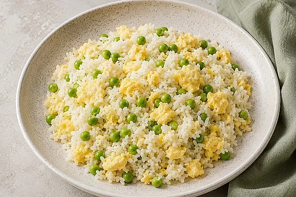 Rice pan with green peas and soft scrambled egg in a light bowl.