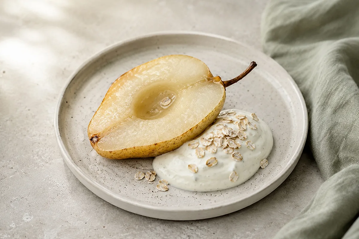 Warm baked pear halves with a spoonful of vanilla quark in a light bowl.