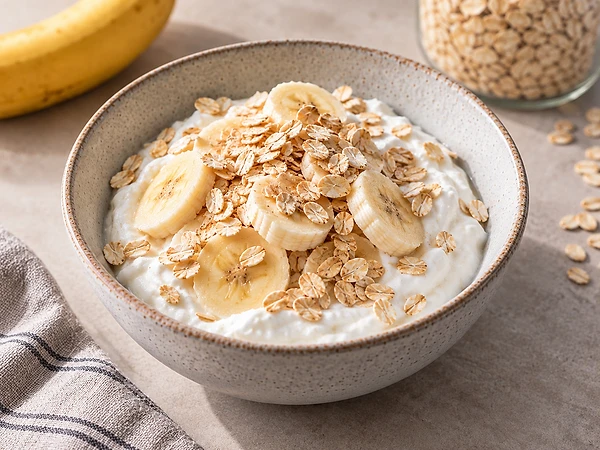 Two bowls of skyr topped with banana slices and rolled oats, dusted with a little cinnamon.