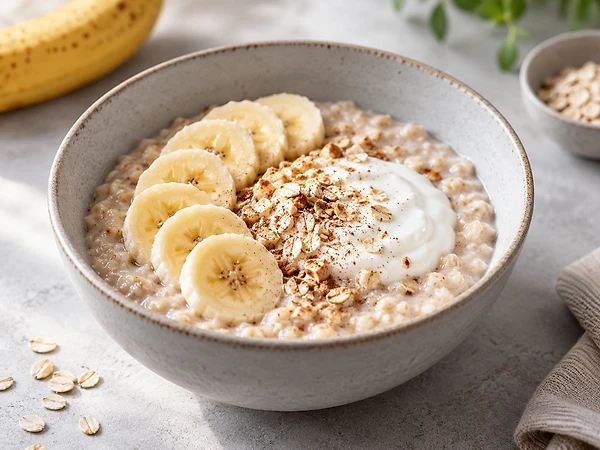 Bowl of creamy oat porridge with skyr stirred in and banana slices on top.