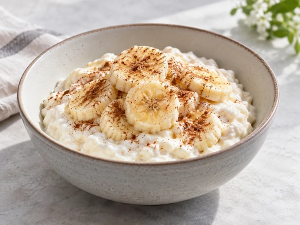 A bowl of creamy low-fat quark with banana slices and a pinch of cinnamon.