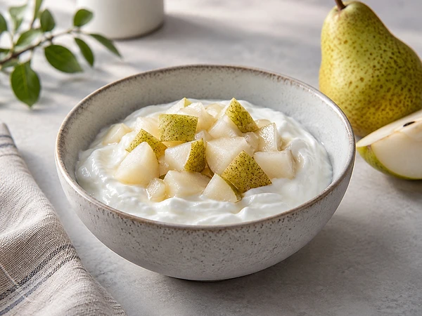 Bowl of creamy skyr topped with warm pear cubes and a pinch of cinnamon