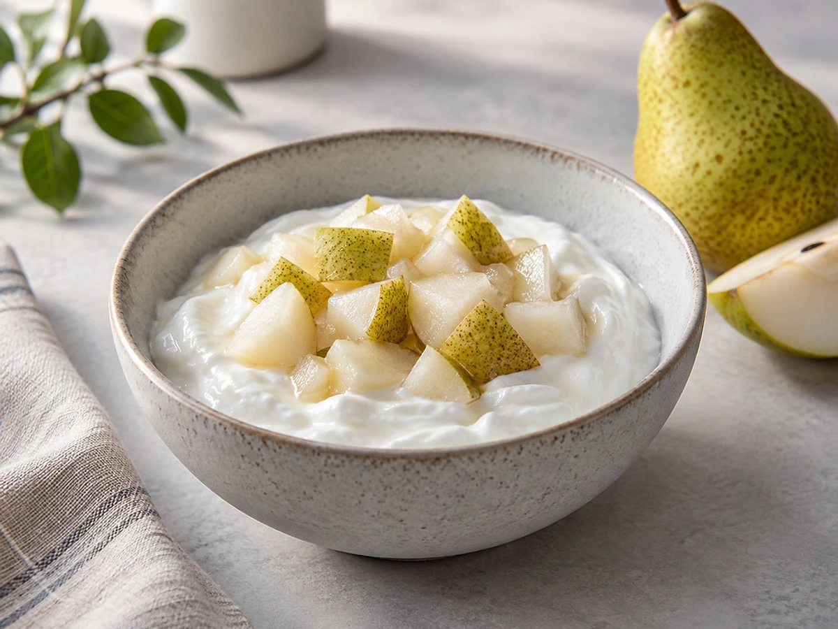 Bowl of creamy skyr topped with warm pear cubes and a pinch of cinnamon